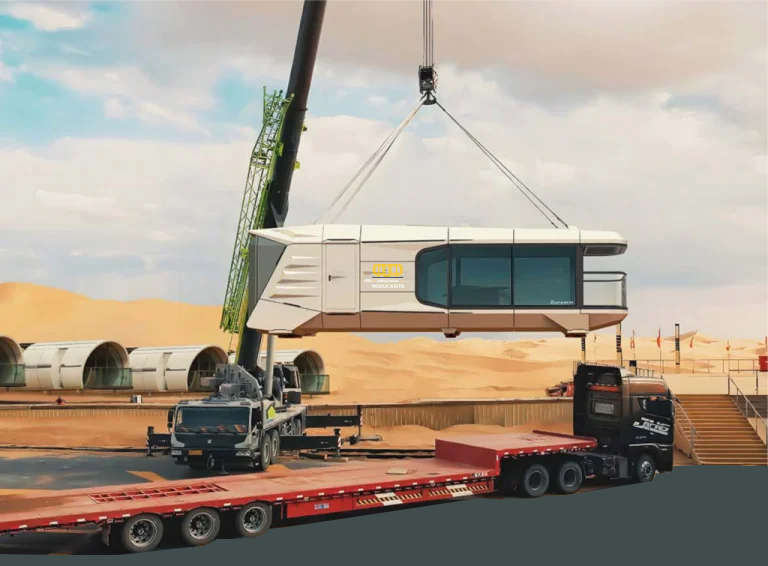 Mobile crane lifting a prefab space capsule house onto its foundation on site